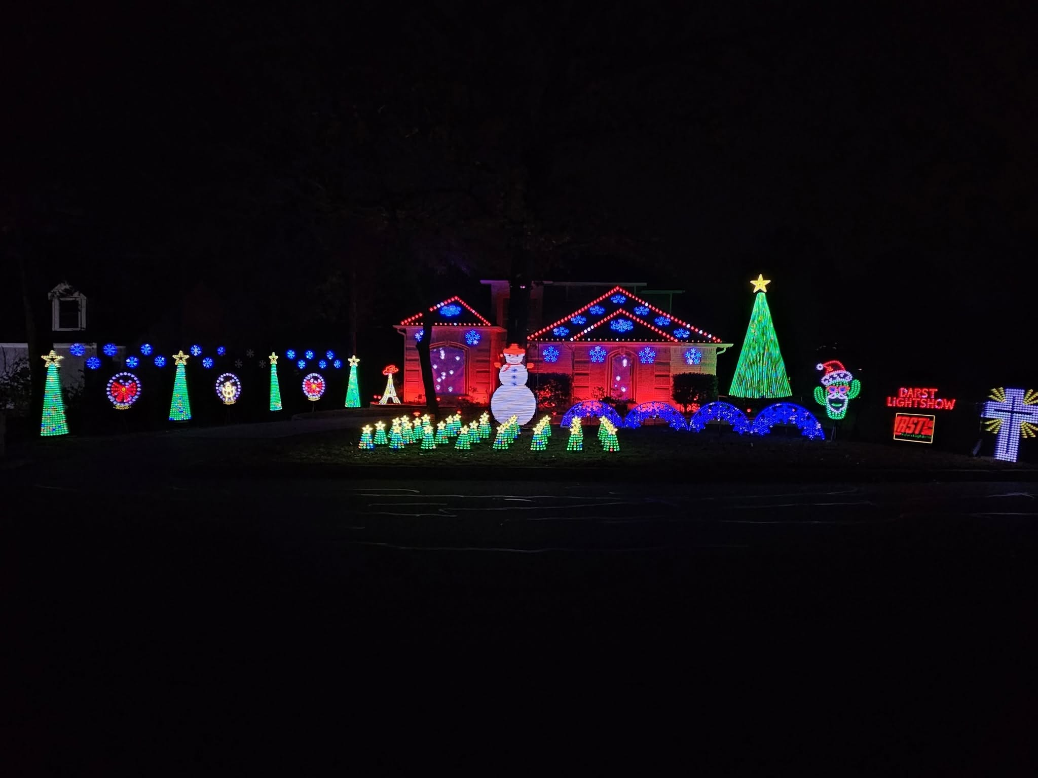 The actual Darst Light Show at Christmas: illuminated rooflines and snowflakes, green pixel trees, a singing snowman, blue arches, and a singing cactus.